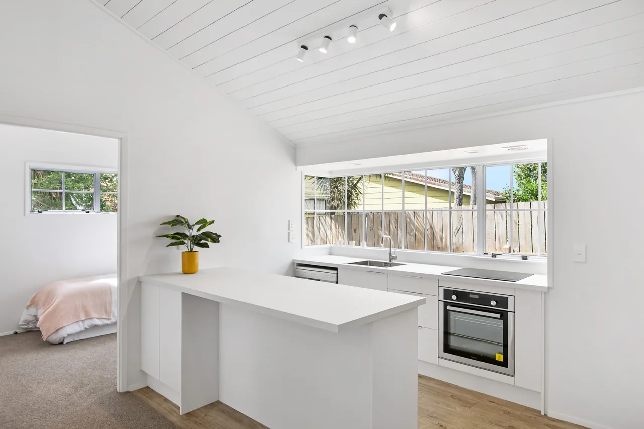 Kitchen with a peninsula and a four-head track light on a raked ceiling above the bench
