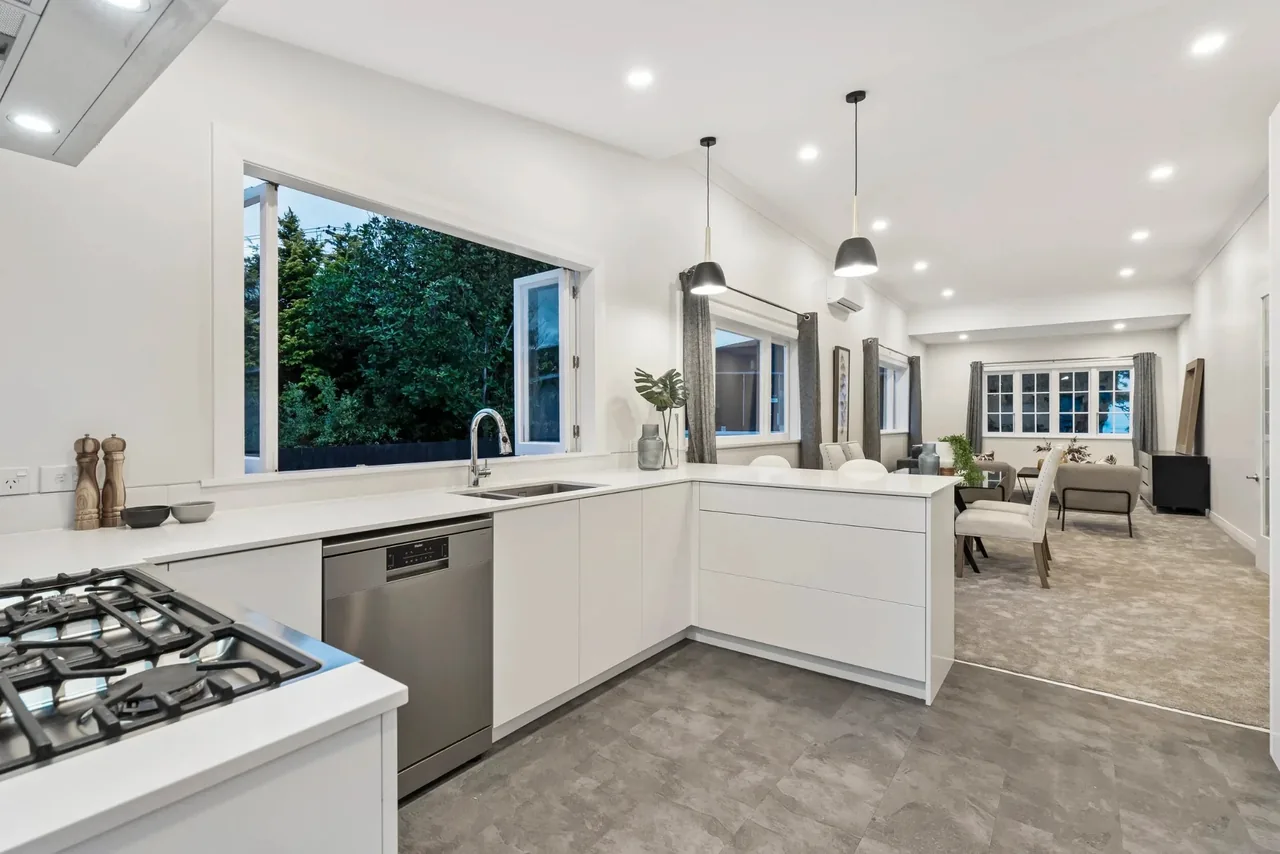 U-shaped kitchen opening to the dining area, with pendant lights, island rangehood lights, and downlights
