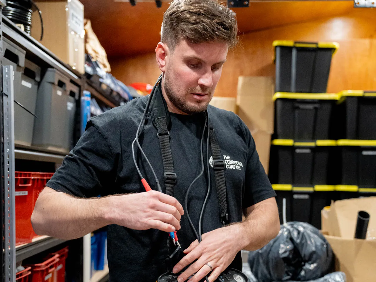 Jordan Statham holding the red probes of a multifunction tester on a chest strap