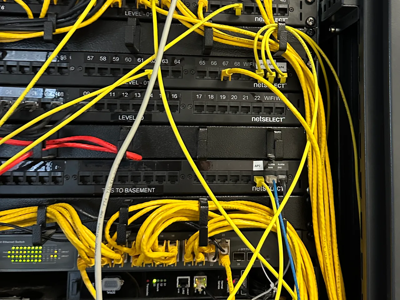 Data rack with labelled patch panels and a mass of yellow patch leads