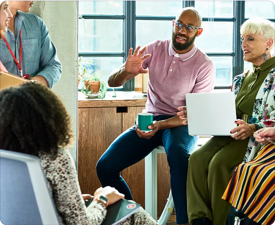man holding coffee mug talking to group