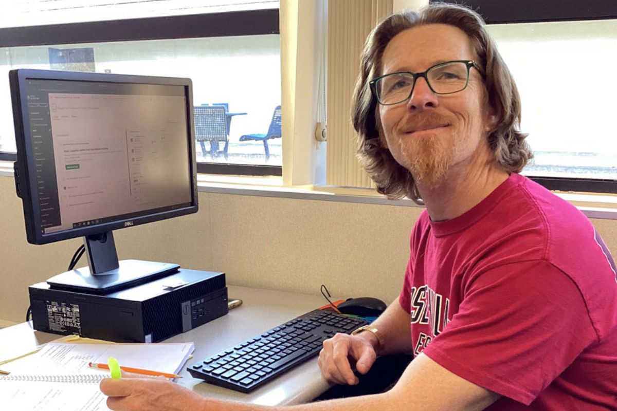 Person working at computer desk with monitor, keyboard, and colorful highlighters