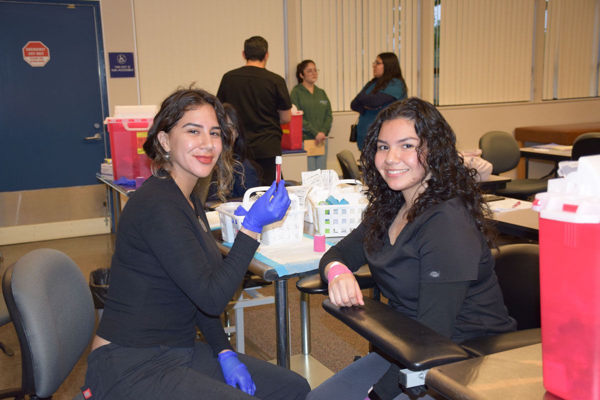 Two medical professionals in black uniforms smiling at medical facility