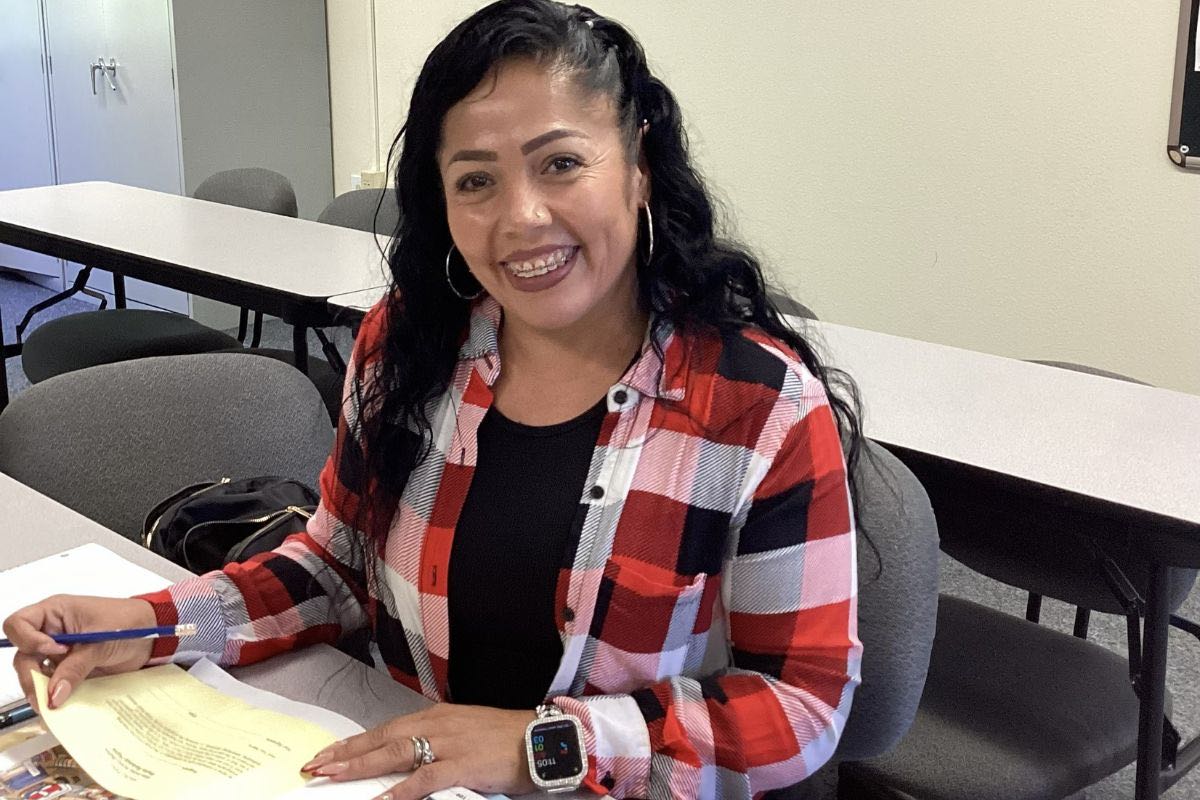 Smiling woman in red plaid shirt working at desk with documents