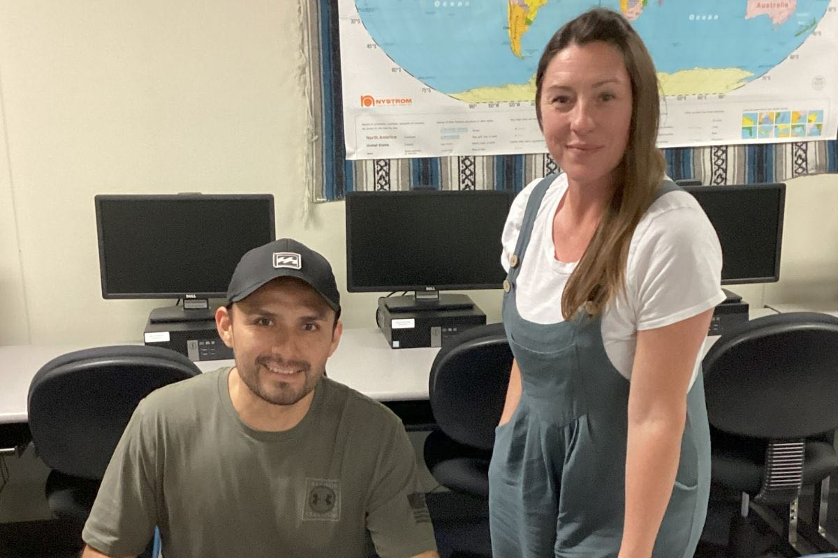Two people in an office with computers and world map background