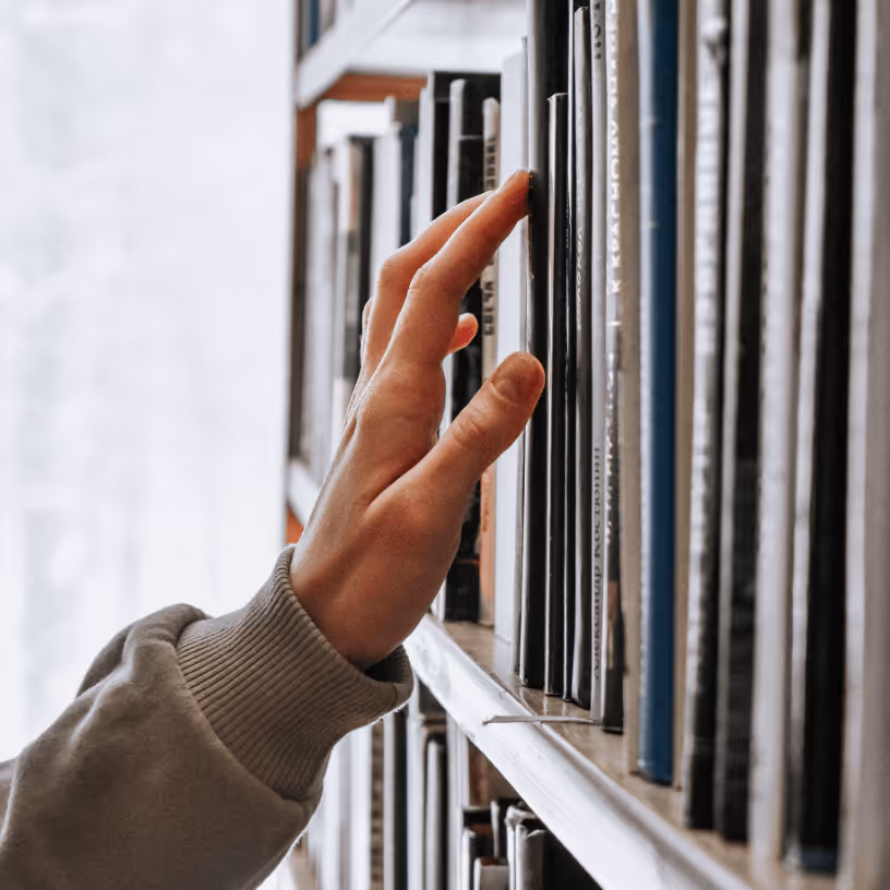 Image of a person grabbing a book off of a shelf