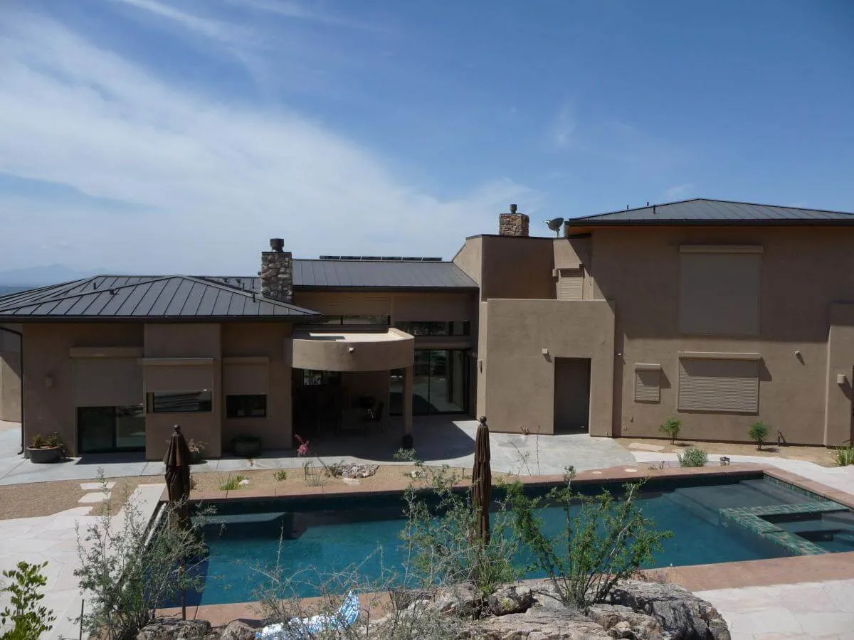 Modern house with pool and covered windows.