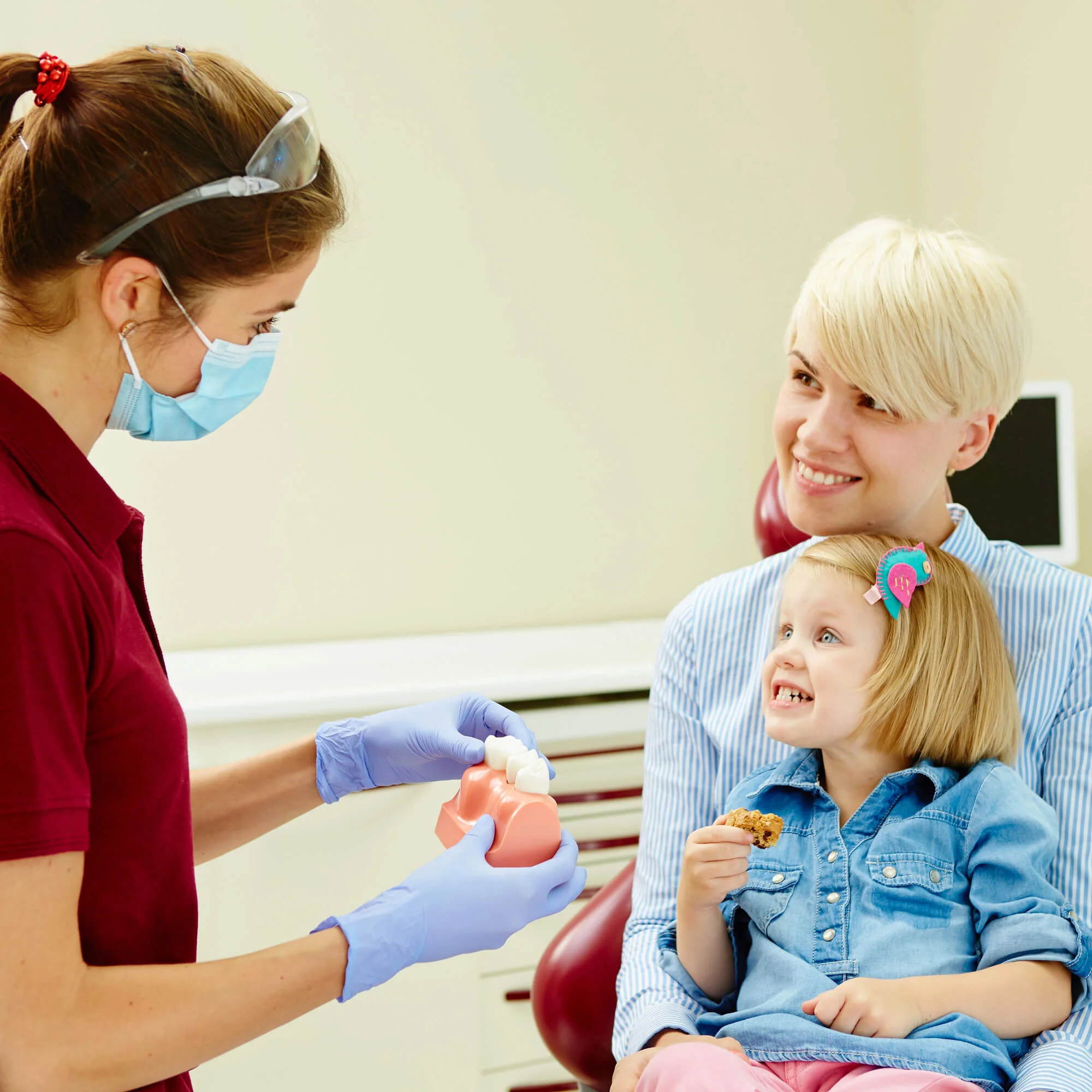 Dentist teaching child with parent nearby, Pediatric Dentist Denver