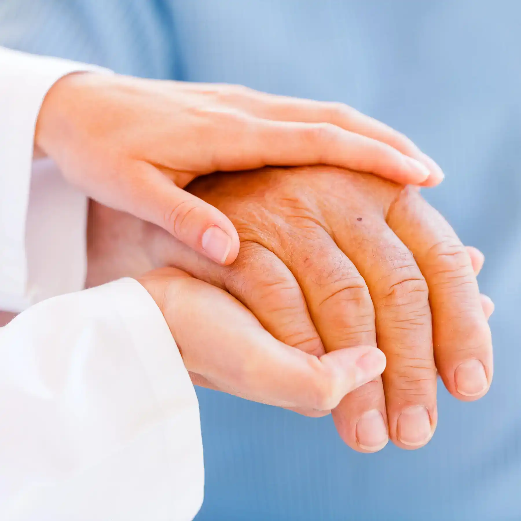 A close-up of a younger person’s hands cradling an older person’s hands.