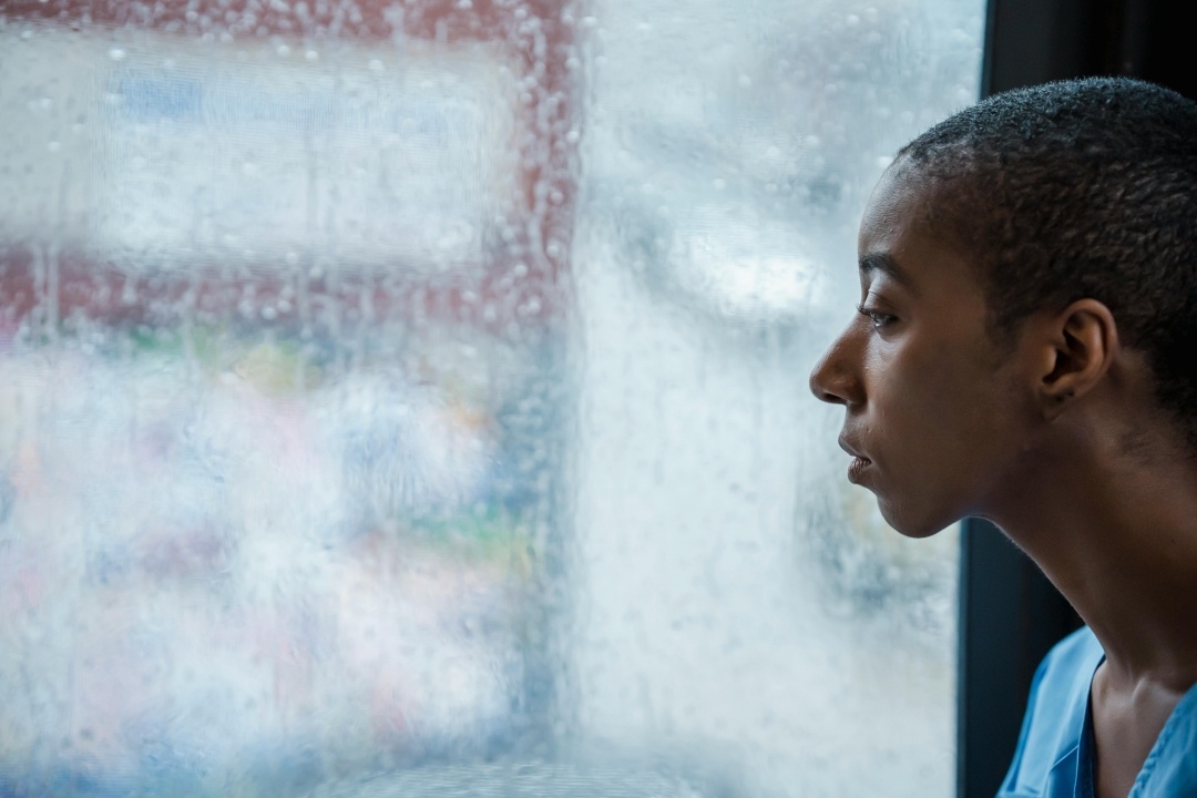 A melancholy woman looks out a rainy window
