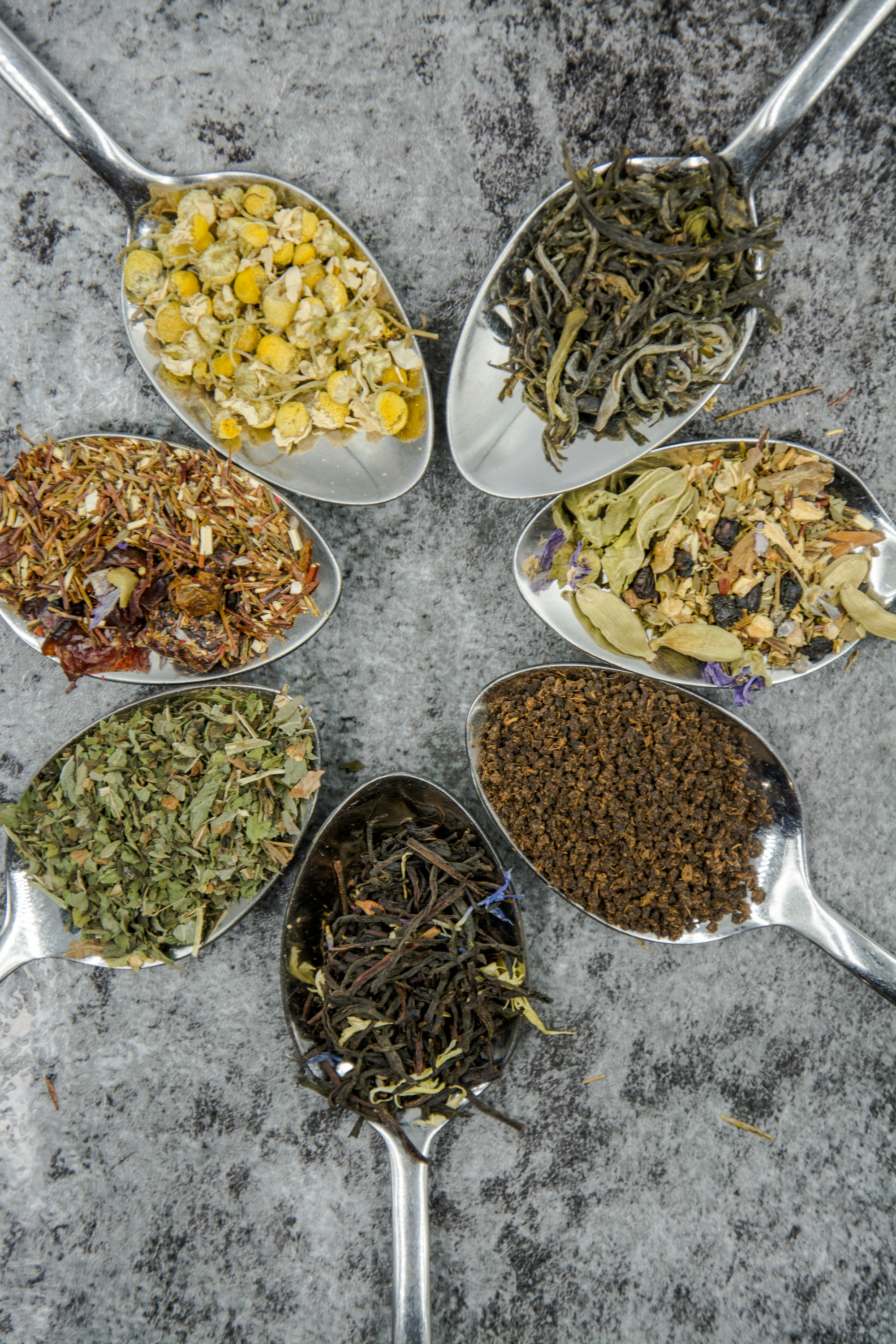 a radial display of spoons containing matchas, oolongs, spices, and botanicals