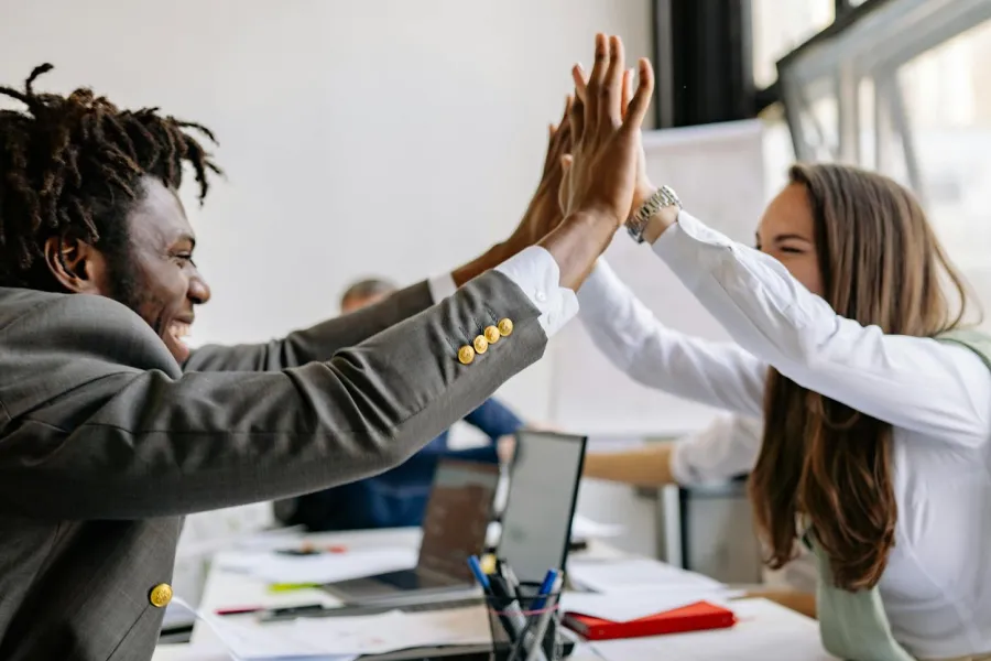 2 coworkers smiling and giving each other a hi-five