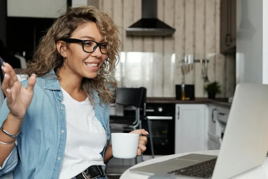 Smiling woman looking at computer and drinking coffee