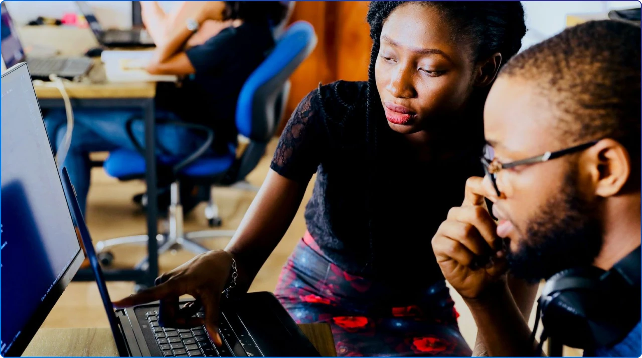 A picture of 2 people working on a laptop