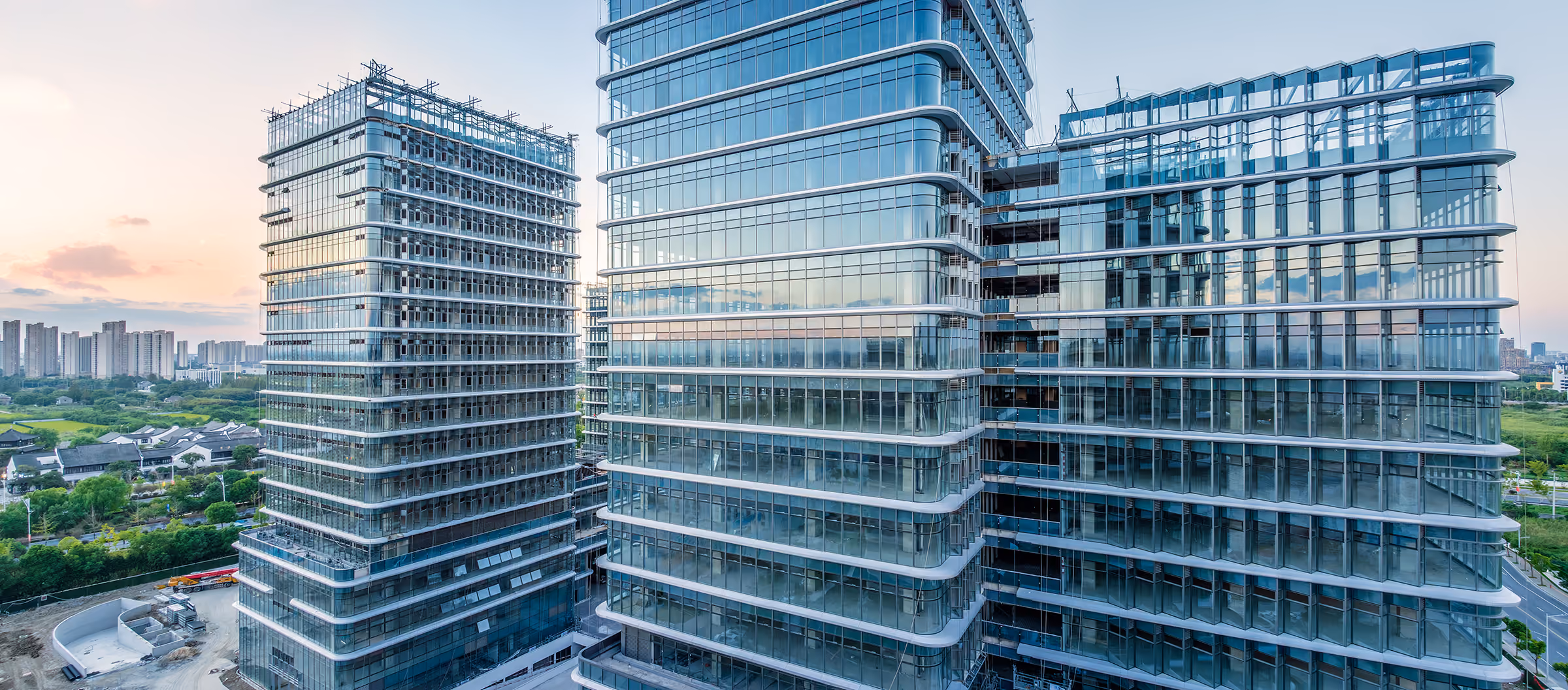 Modern glass office buildings with reflective windows under a clear sky at sunset.
