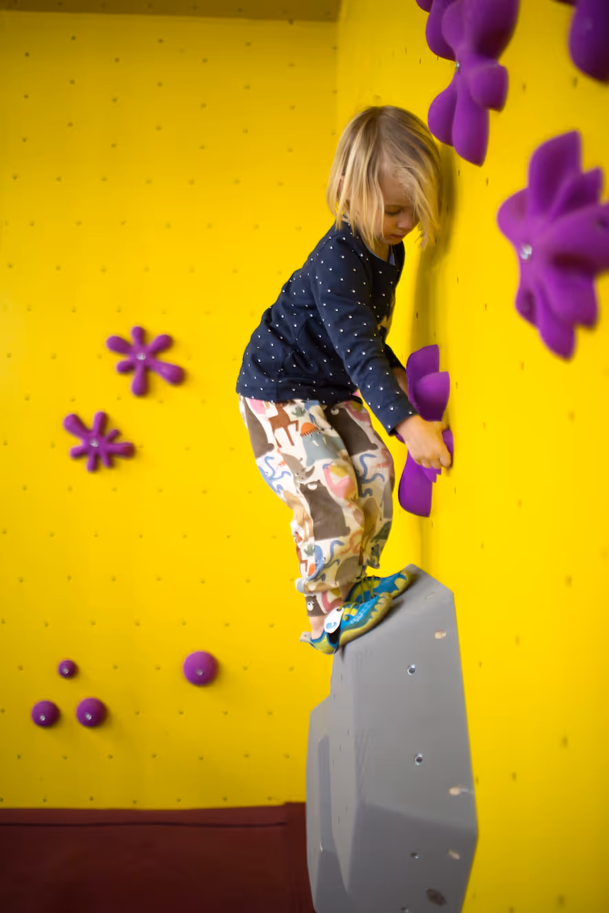 Kleines Mädchen, welches am bouldern ist.