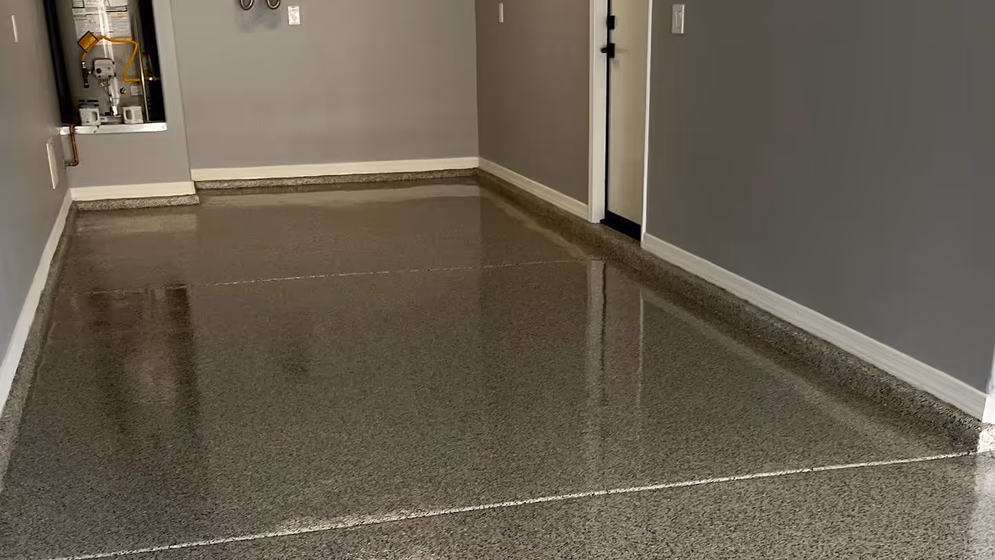 Clean, polished epoxy-coated garage floor with gray walls and a closed door.