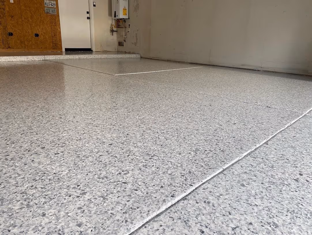 Close-up of a clean, glossy epoxy garage floor with a speckled gray finish and visible seam lines.