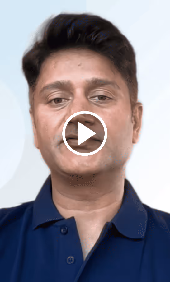 Headshot of a man with short dark hair wearing a navy blue collared shirt against a light background, with a play button overlay.