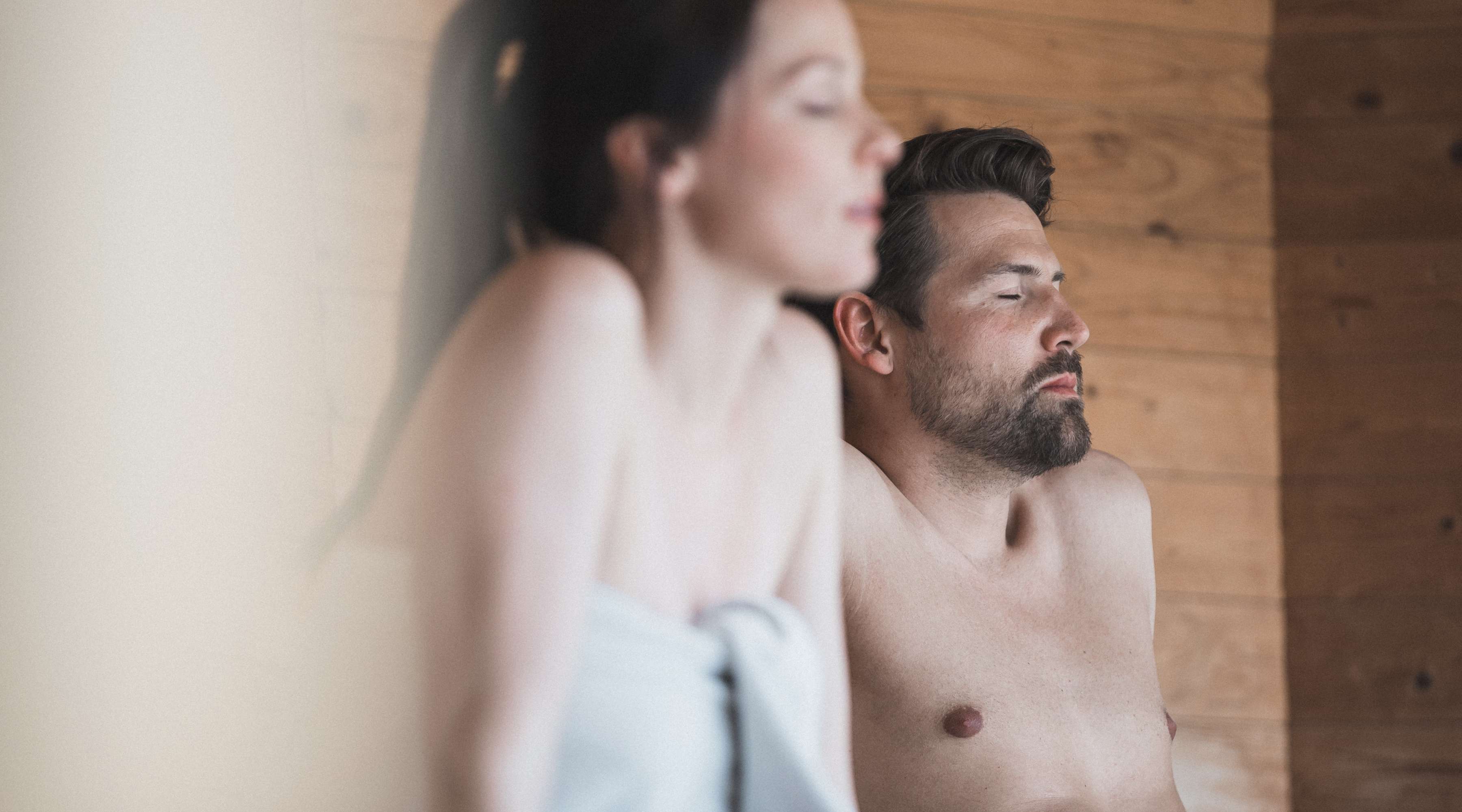 man and woman relaxing in a sauna after a gym workout.