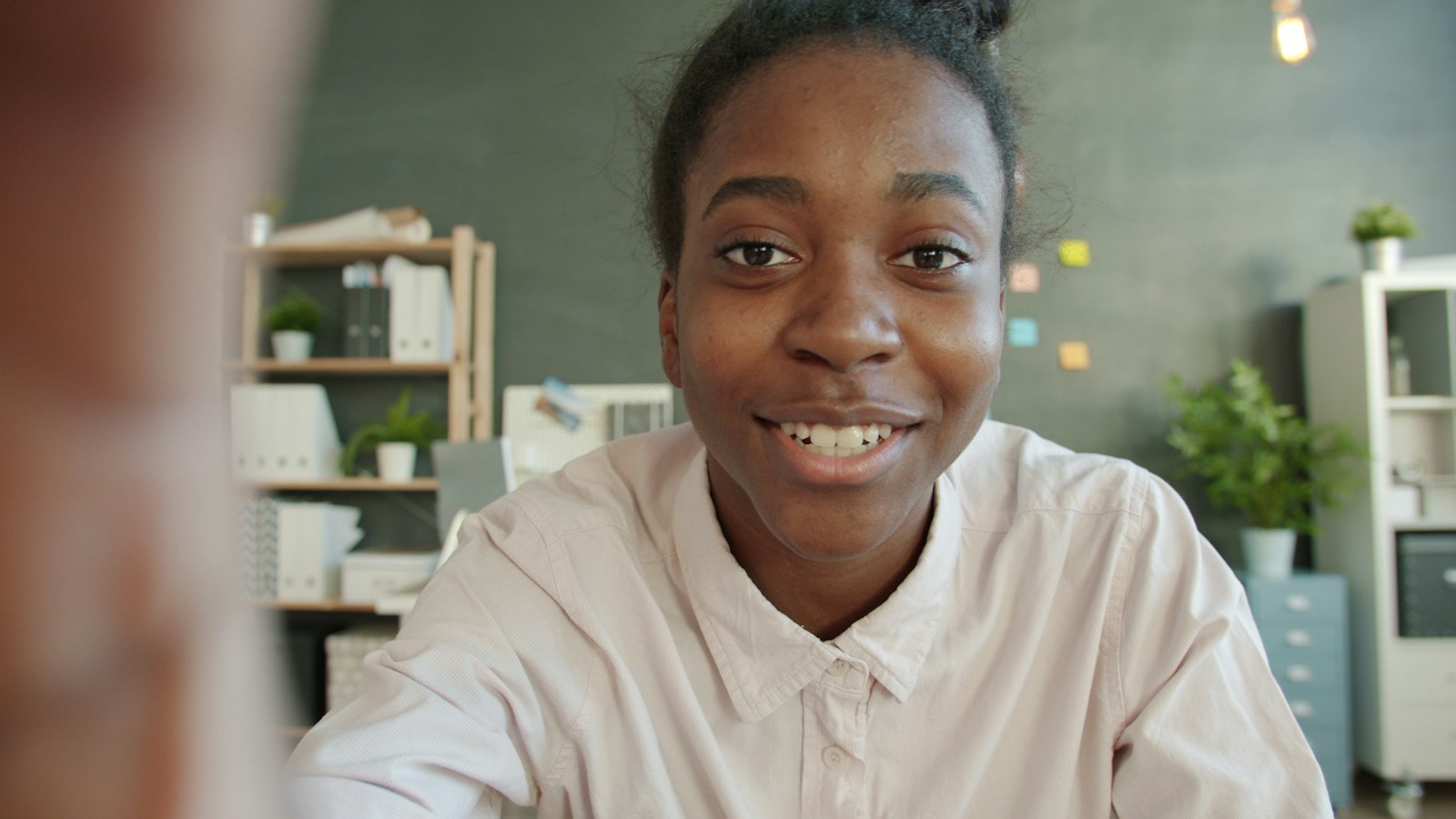 Employee smiling into the camera while recording a testimonial video in the office
