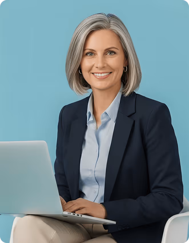 Smiling middle-aged man wearing a light blue shirt sitting in a white chair using a laptop against a blue background.