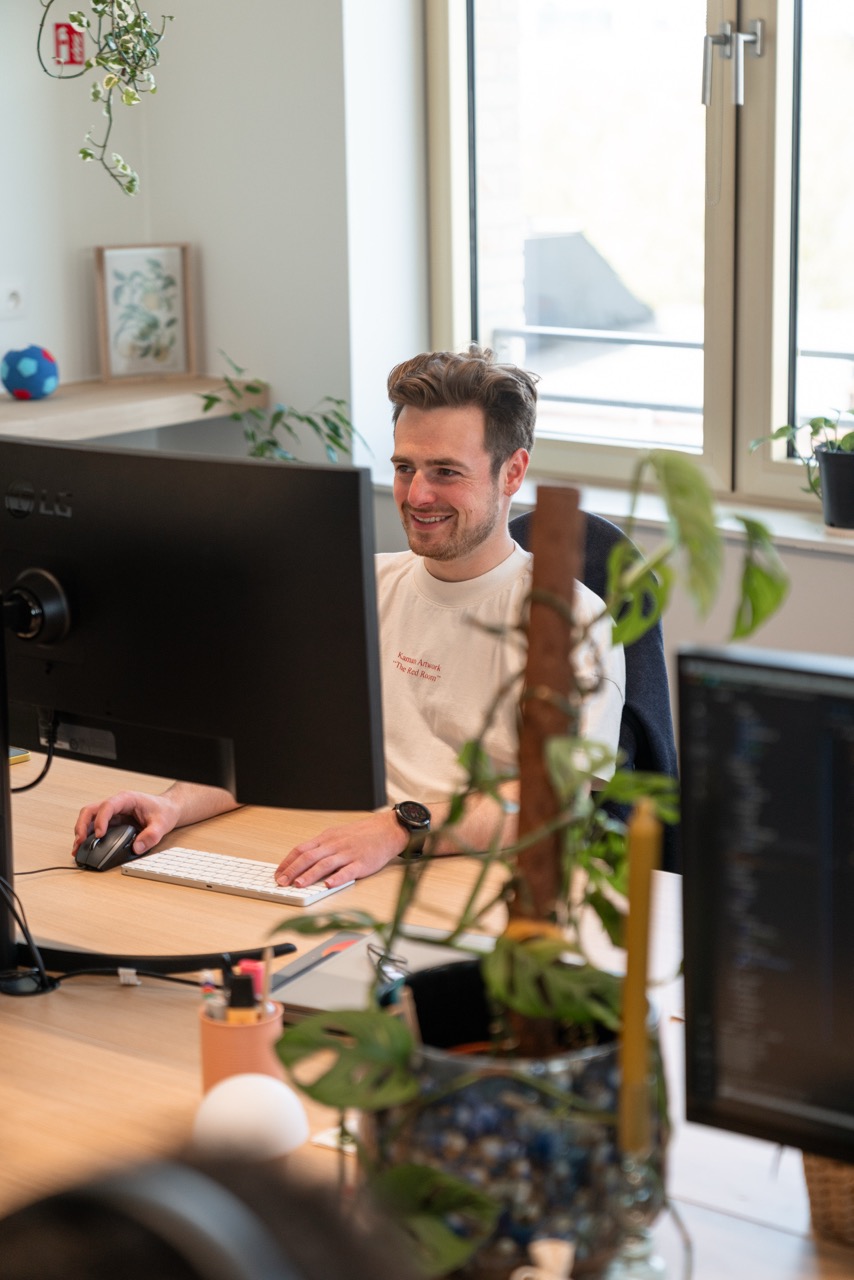 Software engineer working at desk with plants on it