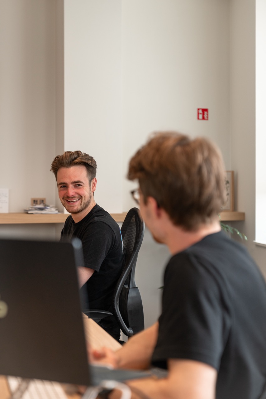 Person behind computer laughing at man next to him