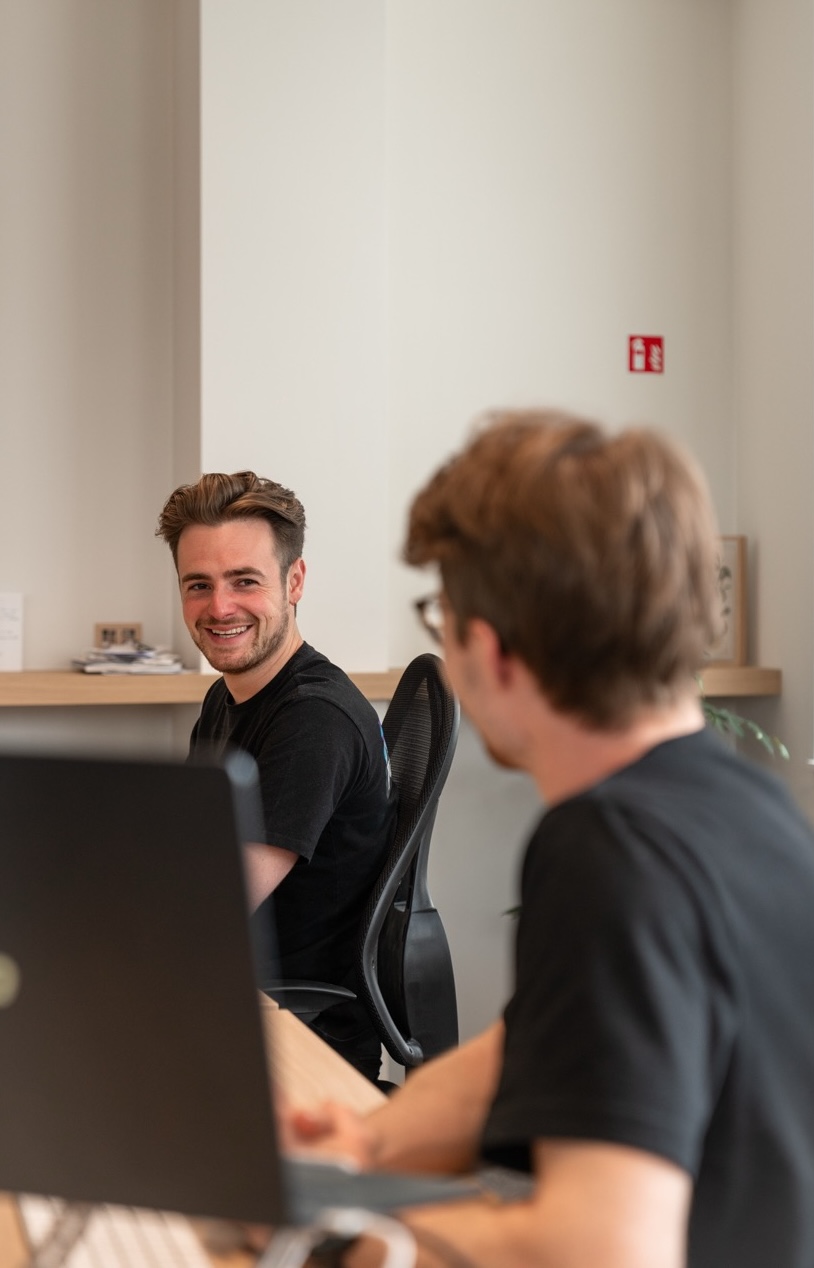 Person behind computer laughing at man next to him