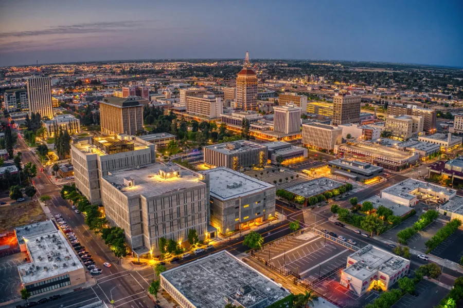 Aerial view of Fresno skyline at dusk with illuminated buildings and streets.