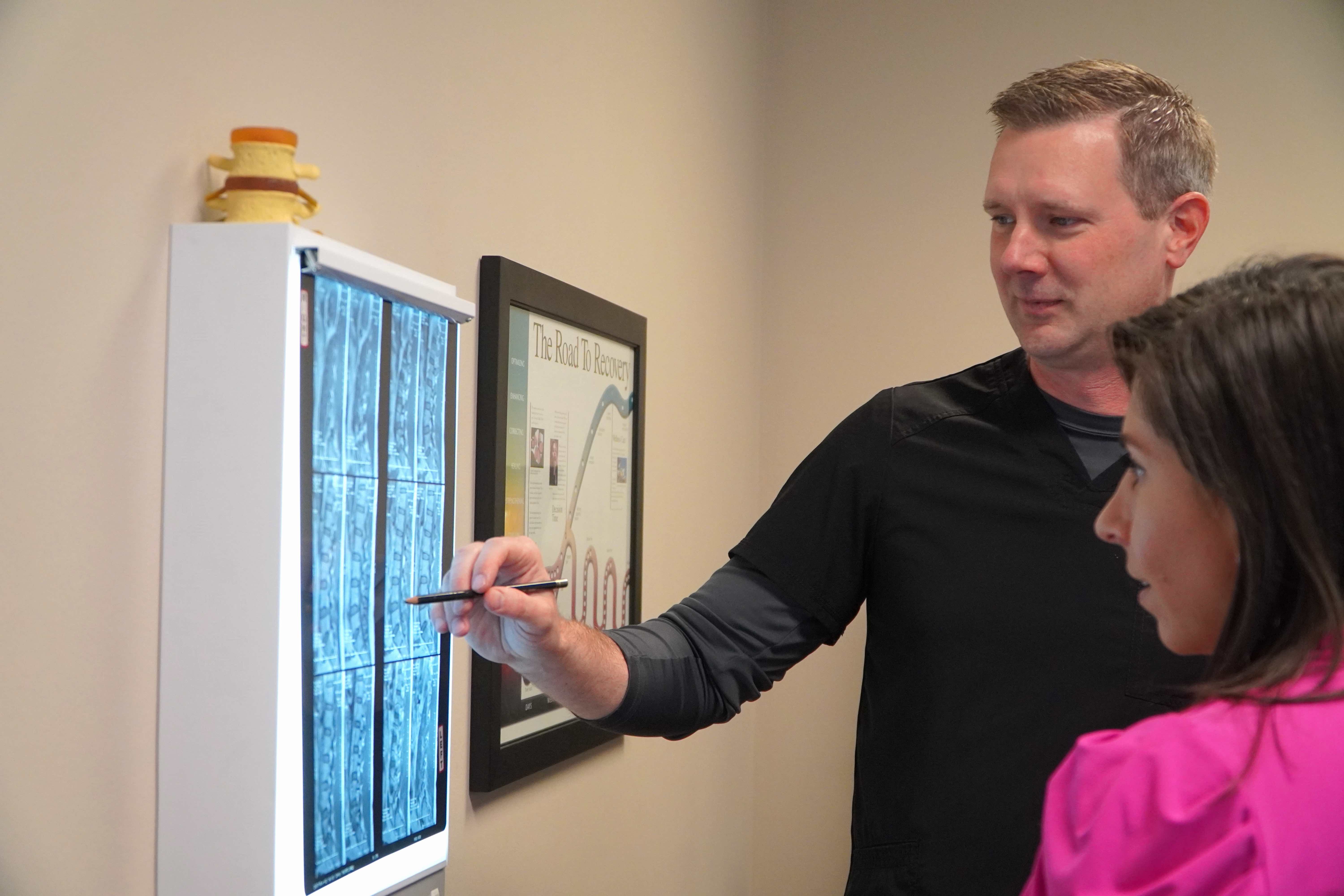 A chiropractor looking at an x-ray with a patient