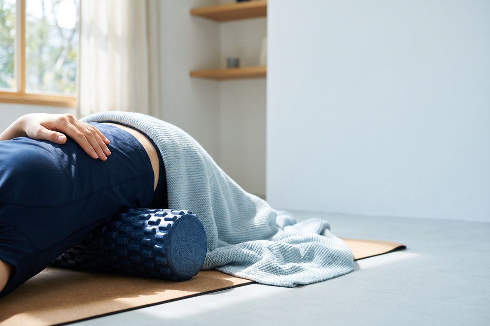 Foam roller beside a person’s lower back during a chiropractic home recovery routine