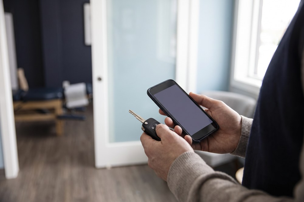 Person holding a car key and phone while arranging a chiropractic visit