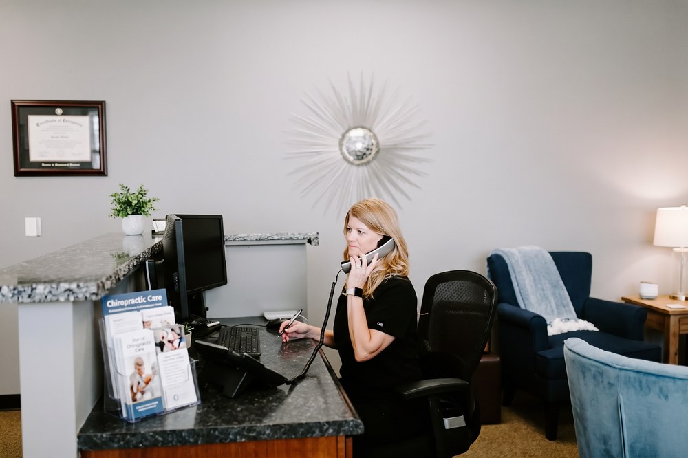 Marshall Chiropractic front-office staff member answering a phone call at the South Tulsa clinic