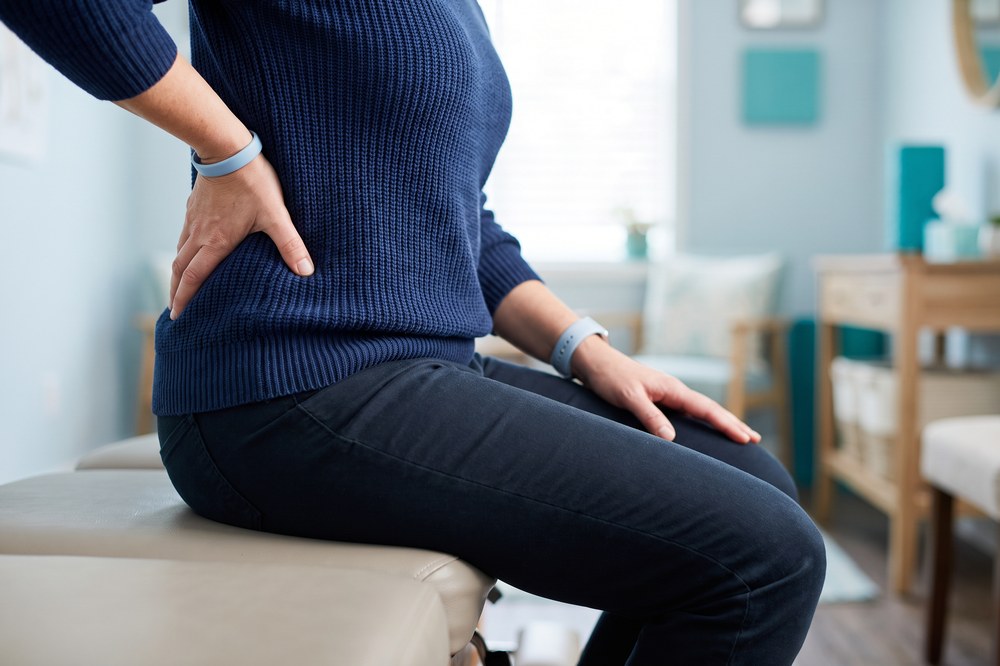 Adult seated on a treatment table supporting the lower back and upper leg