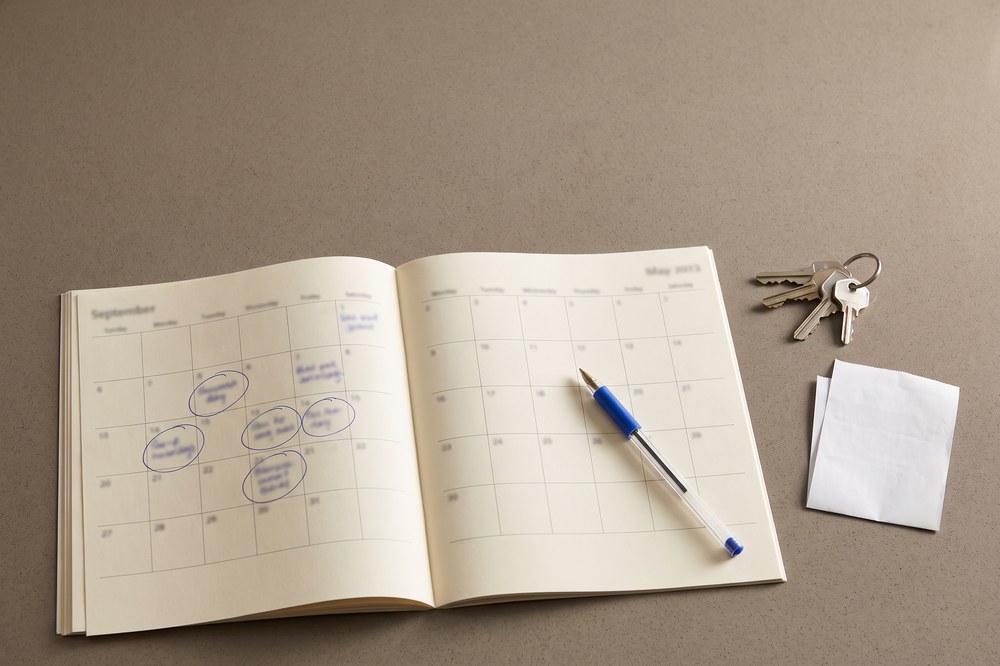 A calendar page on a kitchen counter with several dates circled in pen