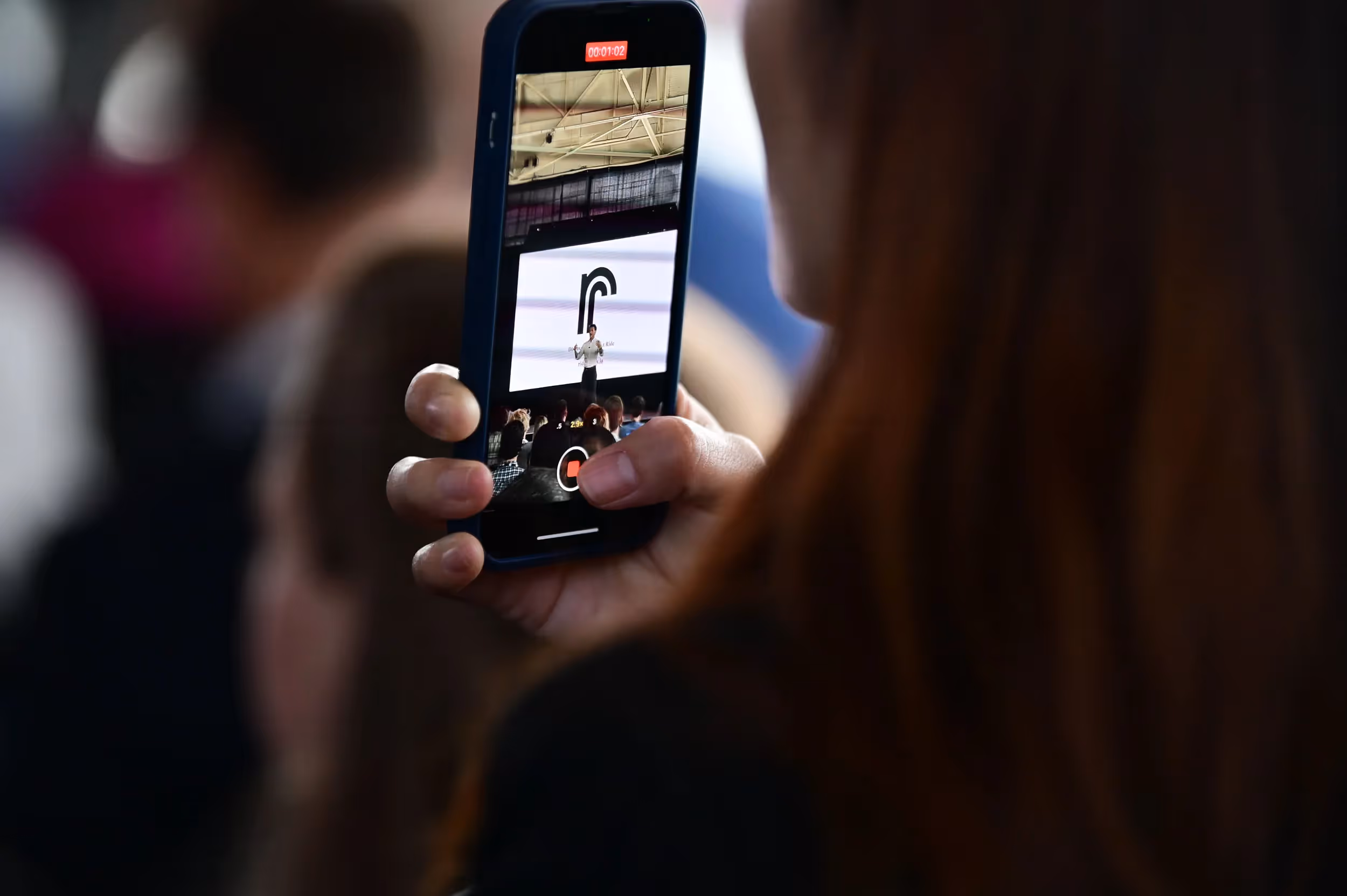 Micromobility America 2022 attendee records video on an iPhone of the Ride Review launch by James Gross, cofounder of Micromobility Industries