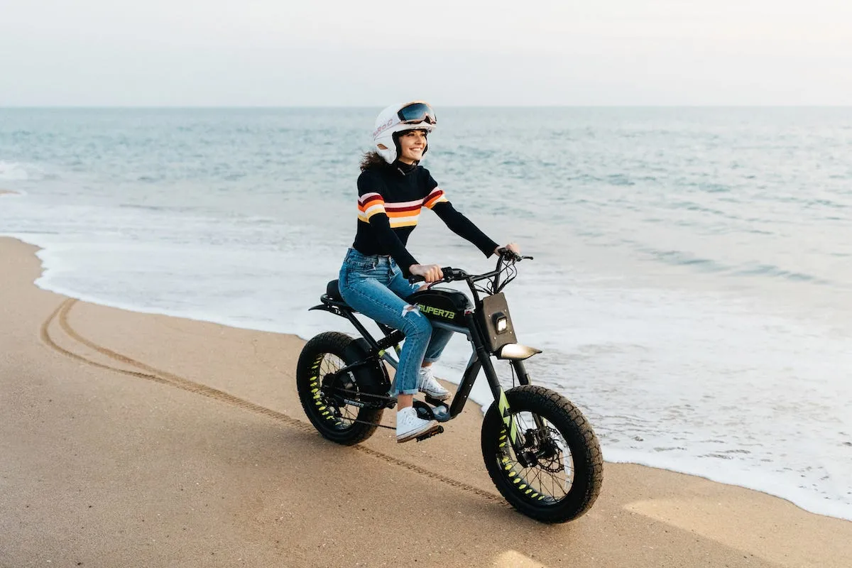 Woman rides Super 73 ebike on the beach near the ocean