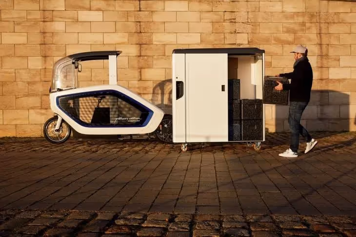 Onomotion e cargo bike and container viewed from the side as a man loads a parcel