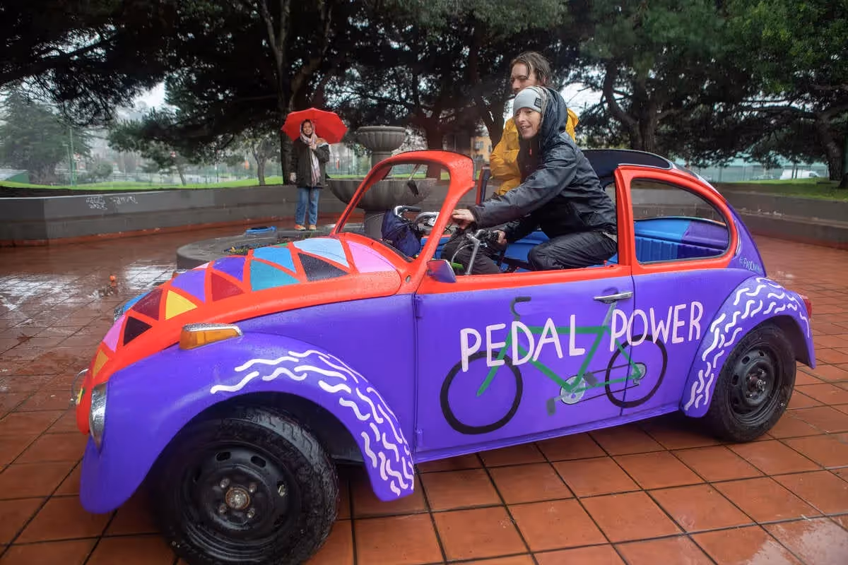 Deborah Gutof (front) drives a bike car created by Eric Schmidt (left) out of the shell of a 1971 VW Beetle named "Pedal Power" at Potrero del Sol Park in San Francisco on Jan. 11, 2023. The vehicle is powered by human power from two bicycles mounted inside the vehicle.