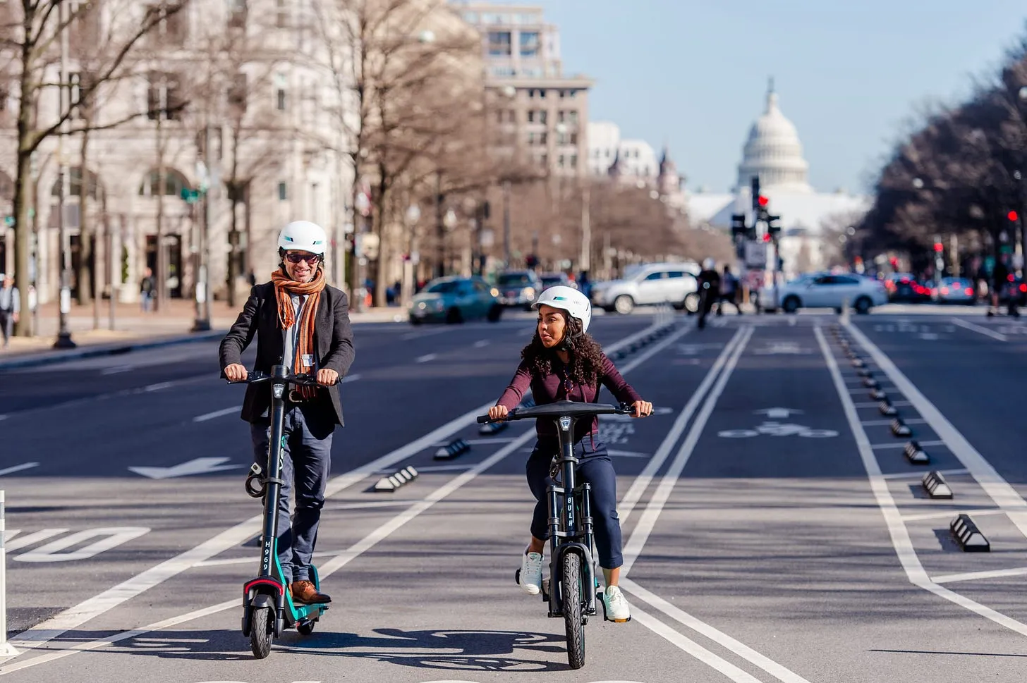 Two people riding vehicles with the capitol in the background