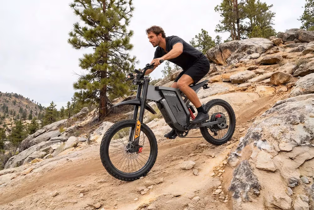 EKXbike X21 Max electric dirt bike with 3000W motor and 19-inch off-road tires being ridden on a rocky uphill trail, showcasing its climbing performance and full suspension