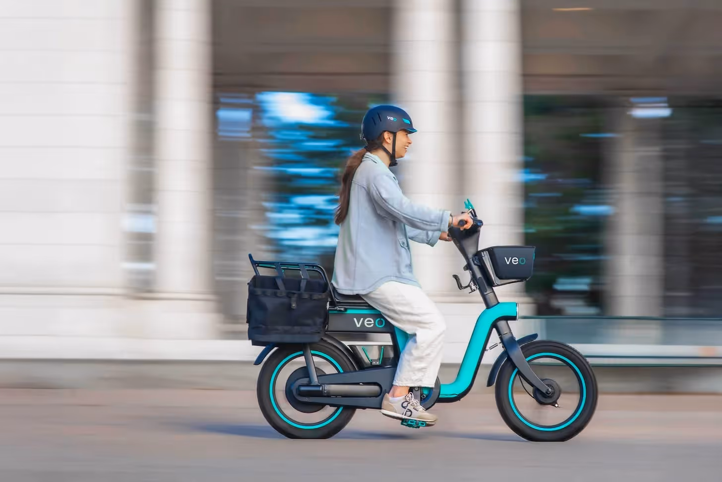 Woman riding a teal cargo e-bike