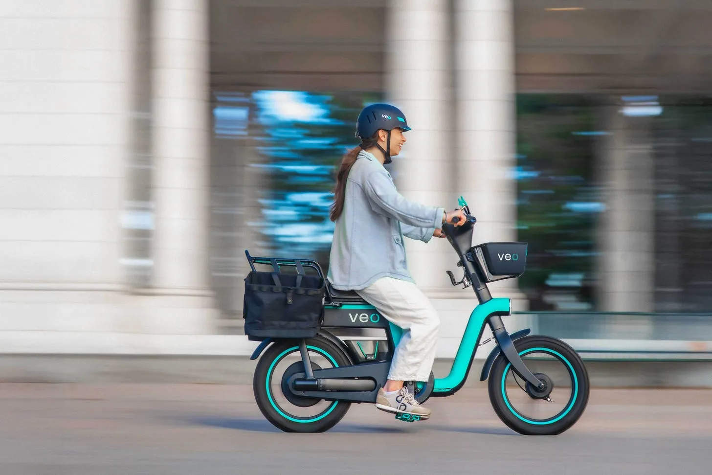 Woman riding a teal cargo e-bike