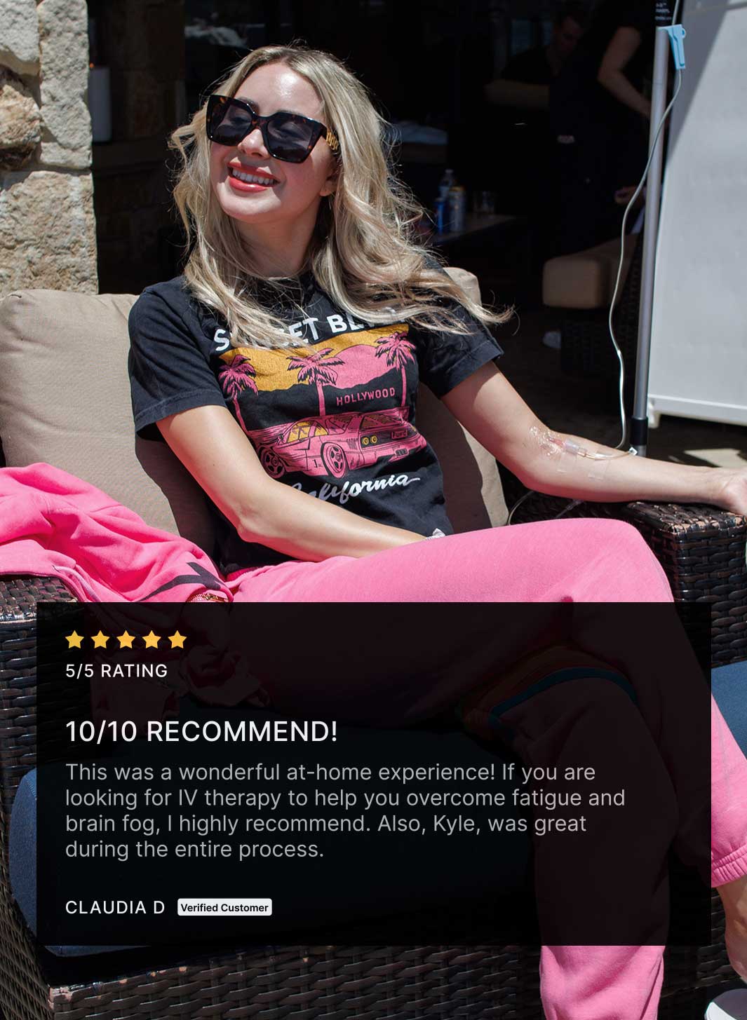 Smiling woman in sunglasses and casual clothes relaxing outdoors while receiving an IV drip, with a 5-star review praising at-home therapy for easing fatigue and brain fog.
