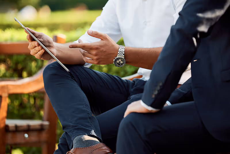 a man sitting on a bench holding a tablet