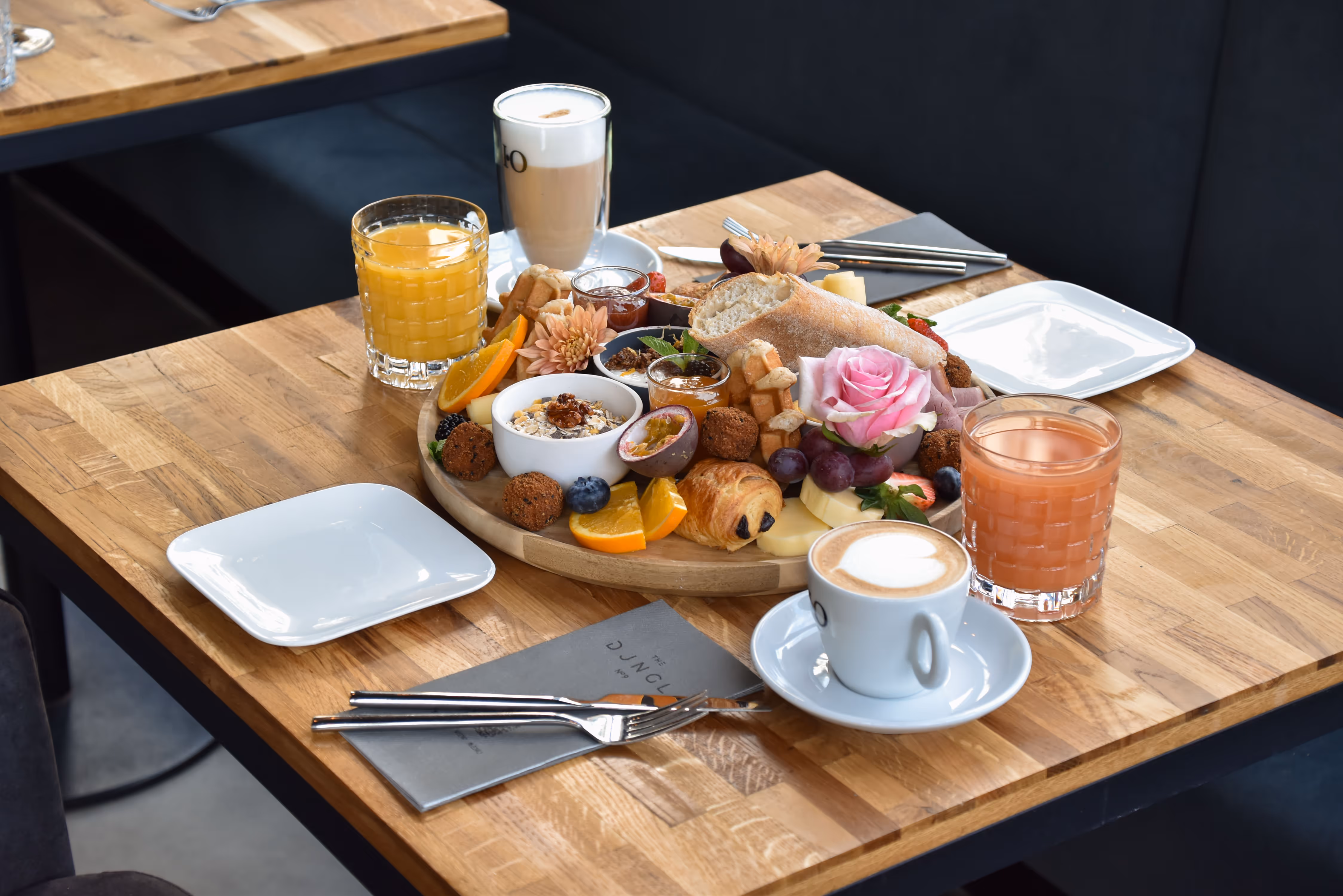 A wooden table topped with a tray of food and drinks.