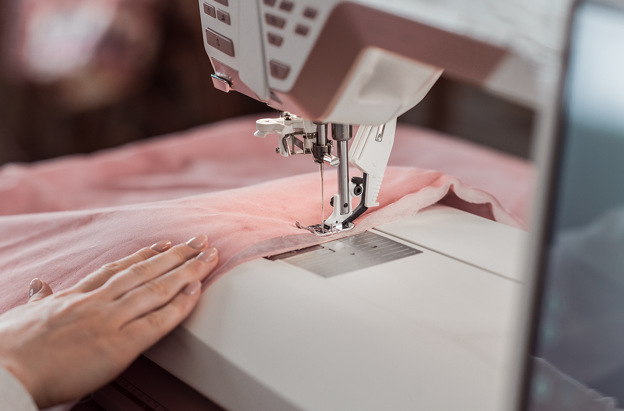 Sewing machine closeup when a woman is sewing on a pink fabric