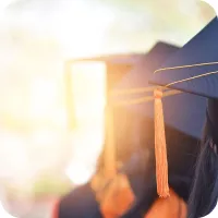 The backs of several people wearing graduation caps and gowns. 