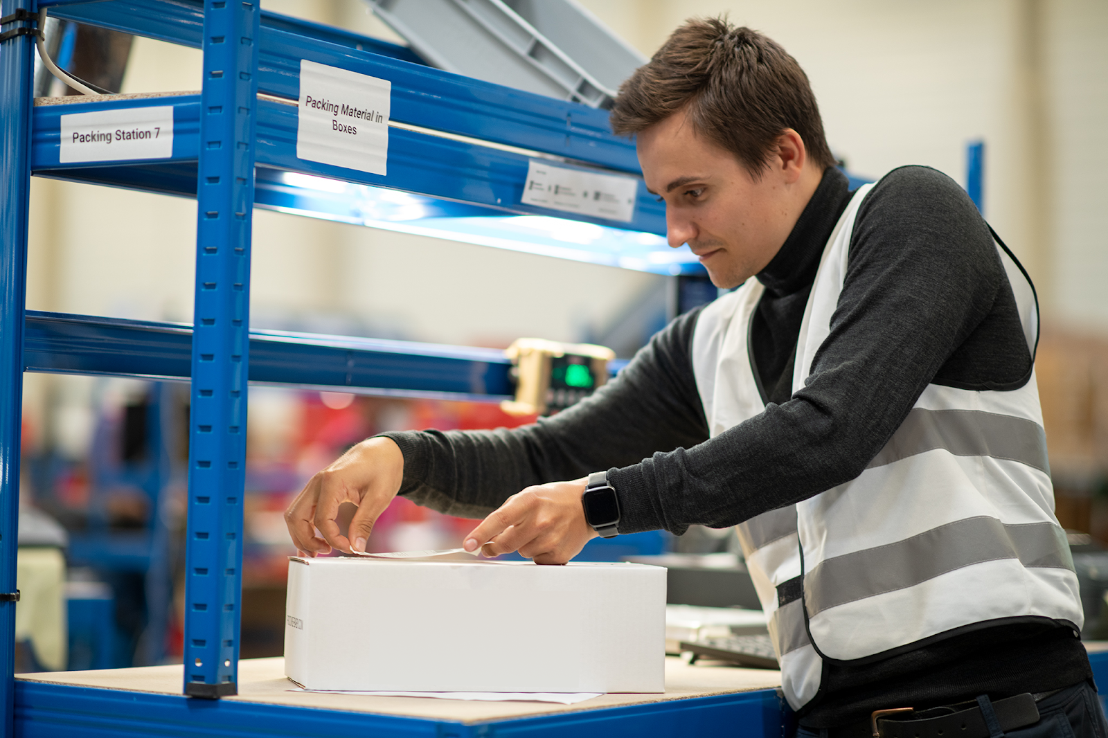 A fulfillment associate packs a box using the Hive WMS